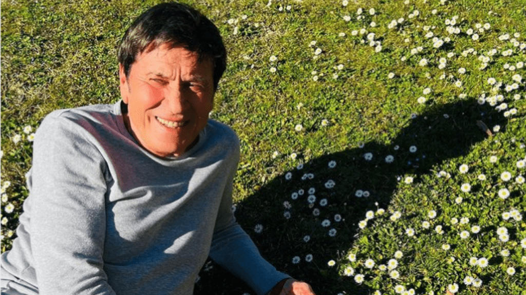 Gianni Morandi coricato su un prato di margherite